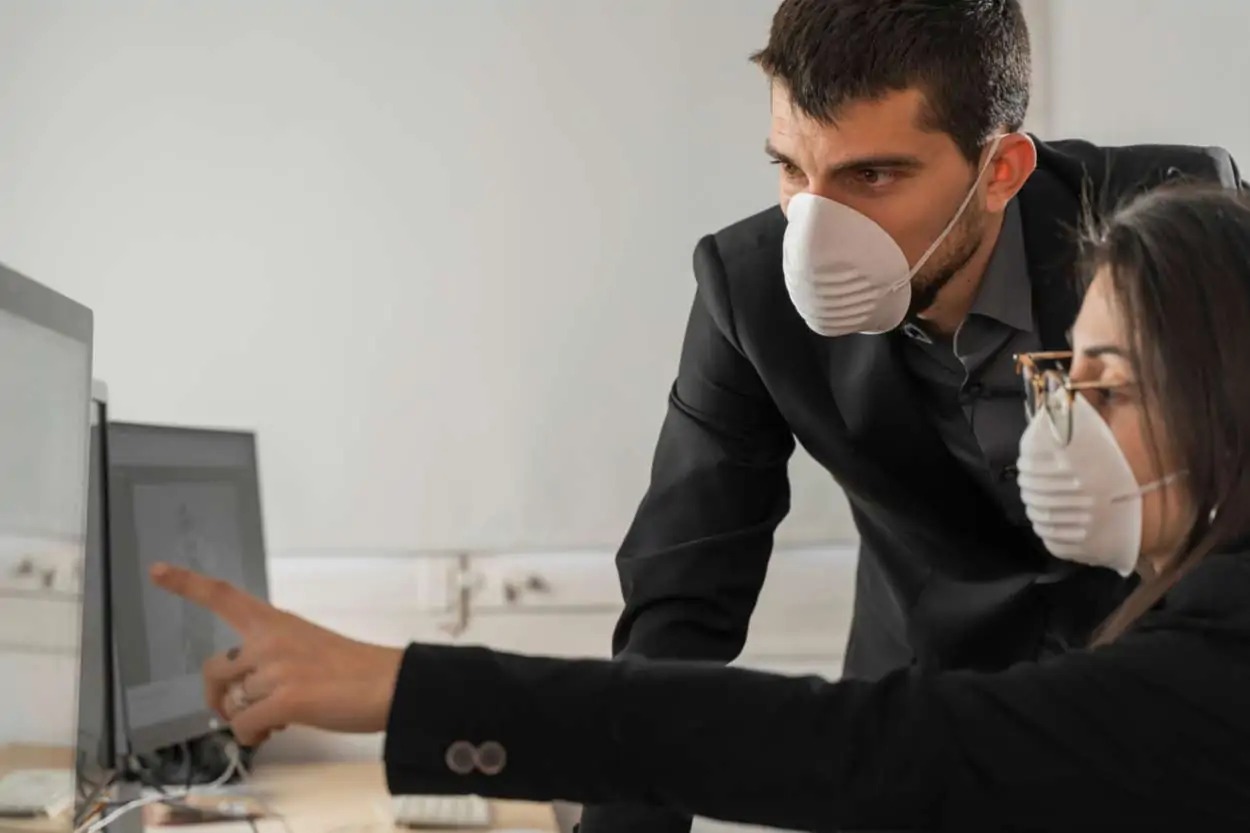 Angestellte mit Gesichtsmaske arbeiten am PC