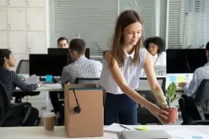 Frau stellt Blumentopf an ihren neuen Arbeitsplatz